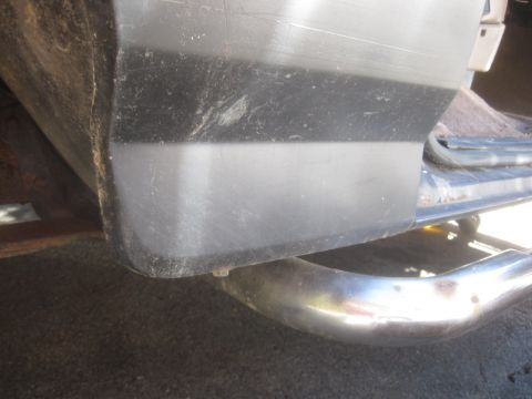 1993 Ford Bronco - Close-up of a vehicle's rear bumper corner and exhaust pipe, with visible wear and tear.