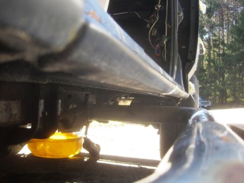 1993 Ford Bronco - The underside of a vehicle is shown with a yellow oil drain pan positioned to catch fluid, and exposed wiring is visible inside the open do…