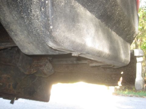 1993 Ford Bronco - The underside of a vehicle is visible, with a focus on the rusty frame and fuel tank components.