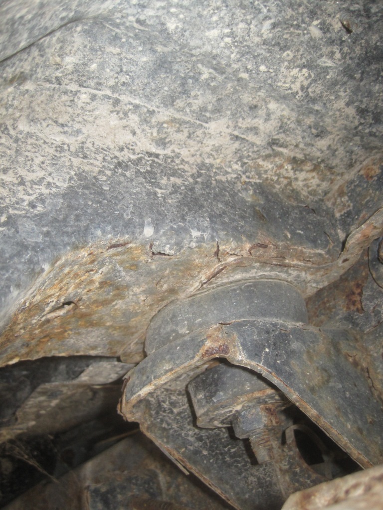 Close-up of rusted metal frame and suspension parts on a vehicle