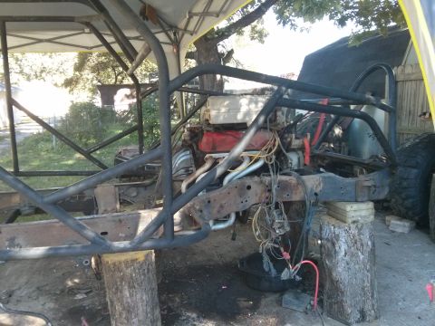 1986 Ford Bronco - The vehicle's frame and engine are exposed, with a custom roll cage installed.