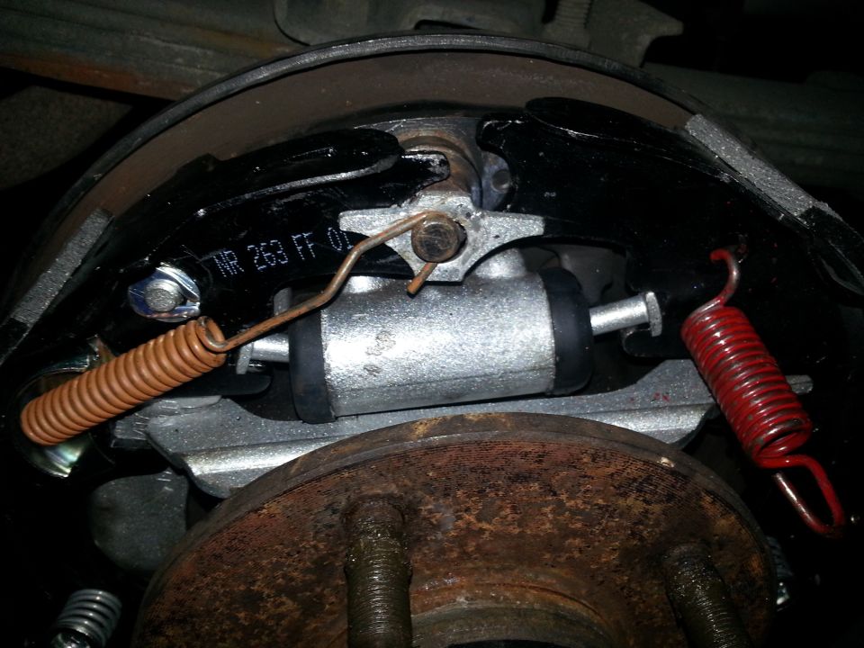 Close-up of a rear drum brake assembly with new brake shoes and springs. Part number NR 263 FF 01 is visible