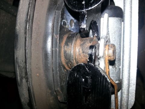 1994 Ford Bronco - A close-up view of a vehicle's rear brake assembly, showing wear and rust on various metal parts.