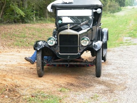 1909 Ford Model T - A person is working on a 1920s Ford Model T, seen from the front.
