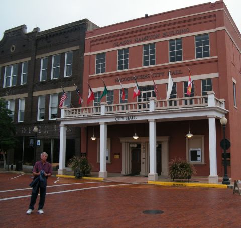 1909 Ford Model T - A man stands on a brick street in front of the Nacogdoches City Hall, a building also known as the Gladys Hampton Building.