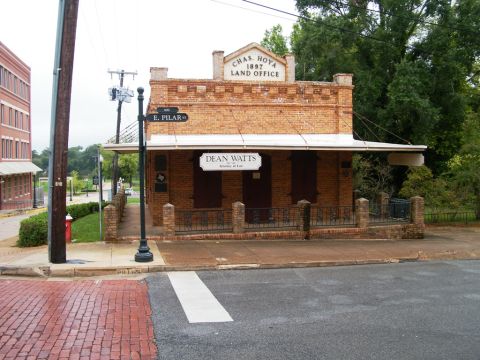 1909 Ford Model T - A historic brick building stands on a street corner, identified by signage as a land office and law office.