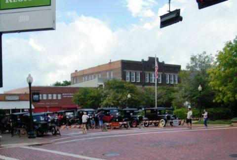 1909 Ford Model T - A gathering of antique automobiles displayed on a cobblestone street with historic buildings in the background.