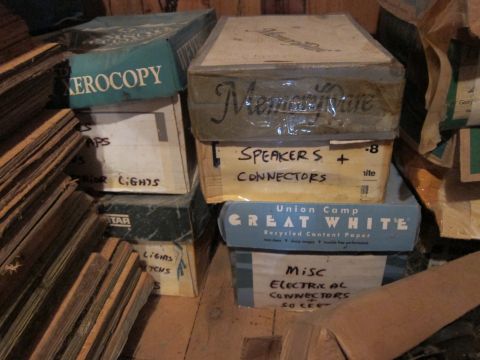 1991 Ford LTD Crown Victoria - A collection of assorted boxes, some with labels indicating their contents, are stacked in a storage area.