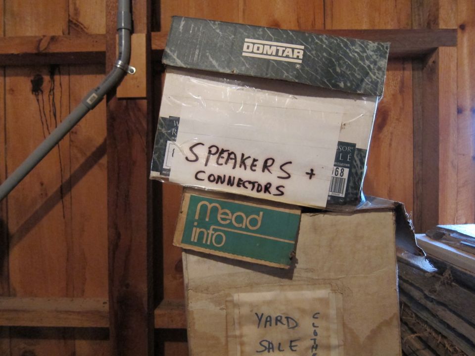 Boxes labeled SPEAKERS + CONNECTORS and Mead info stacked against a wooden wall