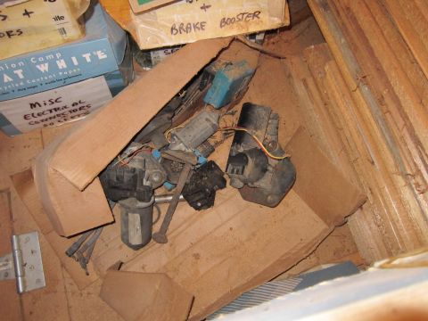 1991 Ford LTD Crown Victoria - Assorted automotive electrical parts and motors piled inside a cardboard box.