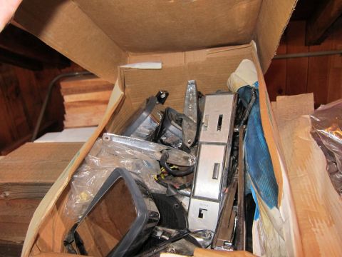 1991 Ford LTD Crown Victoria - A cardboard box is filled with various car parts, suggesting a collection of spare components.
