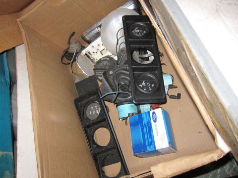 1991 Ford LTD Crown Victoria - A collection of automotive gauges and a blue Ford parts box are shown inside a cardboard box.