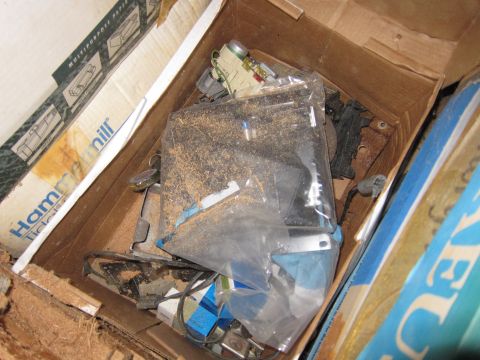 1991 Ford LTD Crown Victoria - A cardboard box contains various electronic components and paper products, suggesting storage of miscellaneous items.