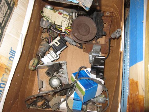 1991 Ford LTD Crown Victoria - A collection of automotive parts, including ignition switches and wiring, is stored in a cardboard box.