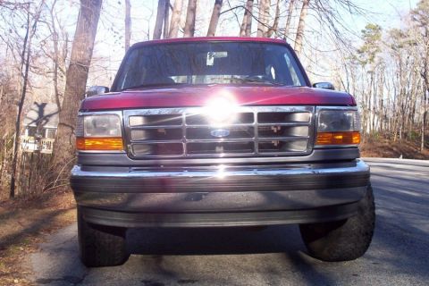 1995 Ford Bronco - Front view of a red 1995 Ford Bronco with a chrome grille and bumper.