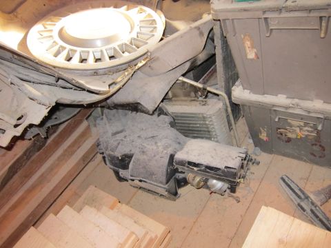 1991 Ford LTD Crown Victoria - A dusty car interior HVAC unit and a hubcap are stored together.