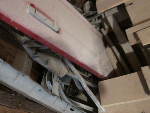 1991 Ford LTD Crown Victoria - A dusty red car door is stored among various metal components and wooden planks.