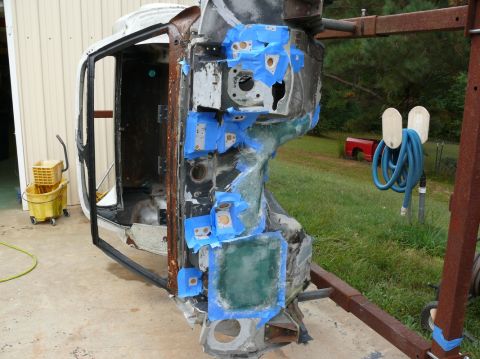 Car frame with blue tape and green filler, viewed from the side