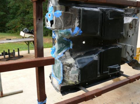 Car frame section undergoing bodywork repairs, taped and covered