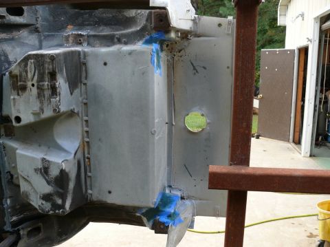 Car frame section with blue tape and a circular opening, viewed from the side