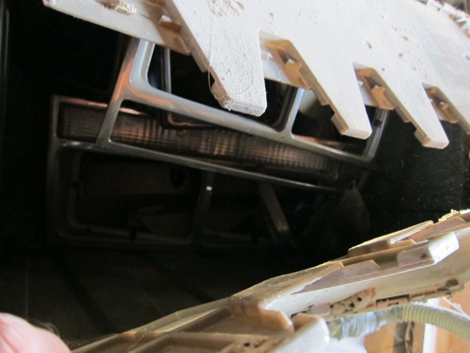 Close-up of a vehicle's front grille and headlight assembly, partially obscured by wooden planks
