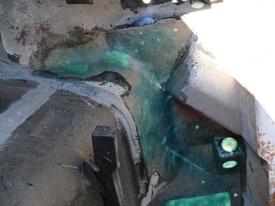 close-up of a vehicle's undercarriage showing a leak of green fluid