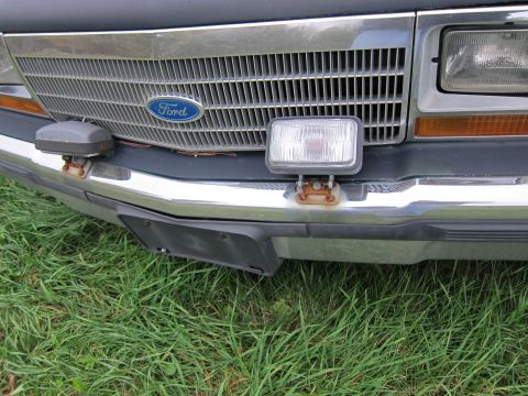 1991 Ford LTD Crown Victoria - Front view of a Ford vehicle's grille and bumper, showing the Ford emblem and auxiliary lights.