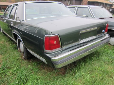 1991 Ford LTD Crown Victoria - Rear 3/4 view of a dark green 1991 Ford Crown Victoria LTD sedan parked on grass.