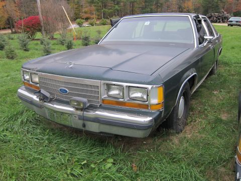 1991 Ford LTD Crown Victoria - Dark green 1990s Ford Crown Victoria with chrome grille and bumper, parked outdoors.