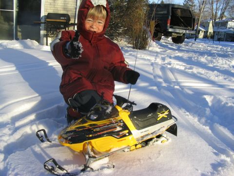 1986 Ford Bronco - Child enjoys a snowy day on a yellow snowmobile.