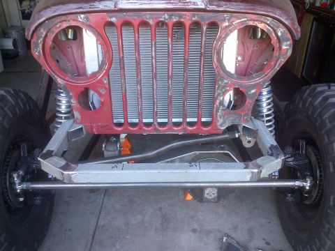 1985 Jeep CJ7 - Front view of a red Jeep CJ7 undergoing modification, showing its iconic grille and suspension components.