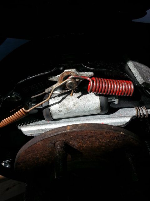 1994 Ford Bronco - Close-up view of a vehicle's rear brake assembly, a red spring and part of the brake drum.