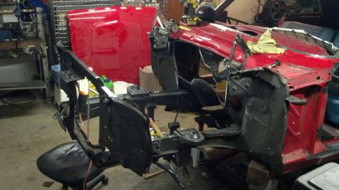 1964 Ford Fairlane - A disassembled red car frame sits in a workshop, awaiting restoration.