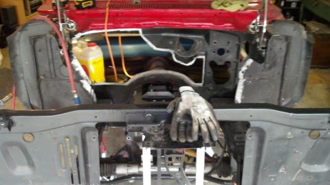 1964 Ford Fairlane - The engine bay of a vehicle is shown during a restoration project, with various parts disassembled and some red paint visible.
