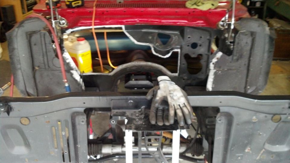 Engine bay during restoration with red paint and a yellow jug