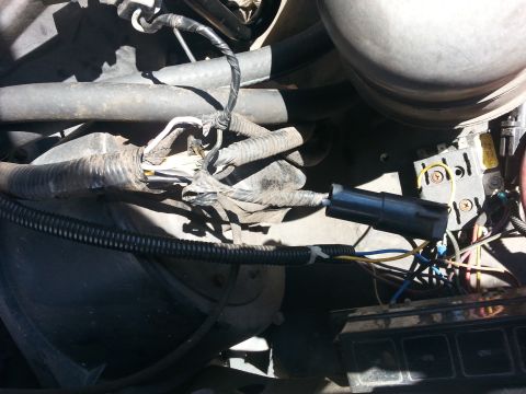 1992 Ford Bronco - Close-up view of a damaged engine wiring harness with exposed wires and a disconnected plug.