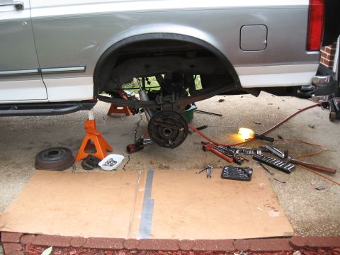 1994 Ford Bronco - Truck rear axle assembly undergoing maintenance with tools laid out on cardboard.