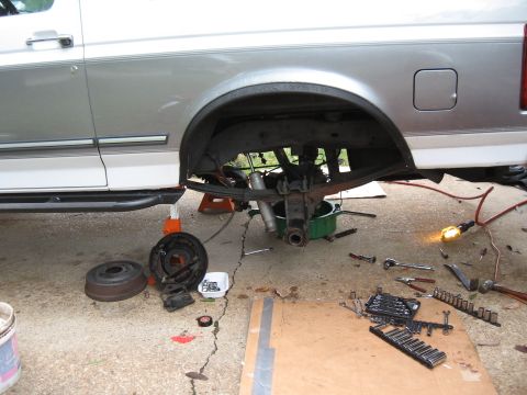 1994 Ford Bronco - The rear axle assembly of a 1994 Ford Bronco is shown removed from the vehicle, with tools and parts scattered around for repair.