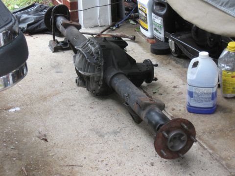 1994 Ford Bronco - A disassembled rear axle assembly rests on a concrete surface, with various bottles and a car part nearby.