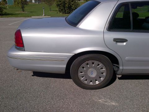 2001 Ford Crown Victoria - The rear passenger side of a silver sedan is shown parked on asphalt.