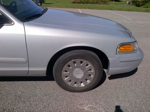2001 Ford Crown Victoria - A silver 2001 Ford Crown Victoria is seen from the front quarter angle, showing its front fender and wheel.
