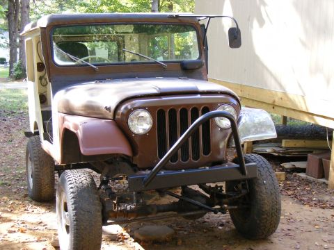 Brown Jeep CJ-5 with a custom bumper and wooden rear bed, front 3/4 view