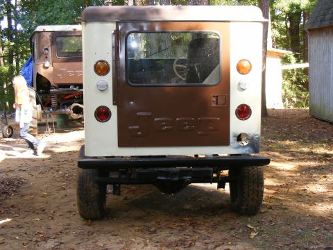 Rear view of a tan and brown Jeep CJ-5 with "JEEP" embossed on the tailgate