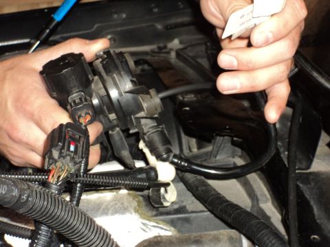 2004 Mercury Grand Marquis - Close-up of hands manipulating electrical connectors and hoses on a vehicle engine component.