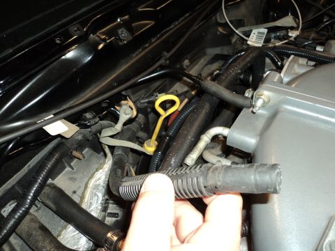 2004 Mercury Grand Marquis - A hand holds a disconnected ribbed hose near engine components.