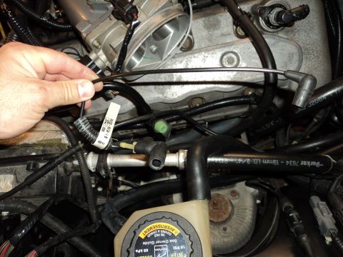 2004 Mercury Grand Marquis - Close-up view of an engine bay, focusing on a hand manipulating a spark plug wire amidst various hoses and mechanical parts.
