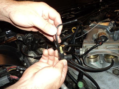 2004 Mercury Grand Marquis - Close-up of hands connecting a vacuum line to a throttle body assembly, with visible SuperMotors.net watermark.