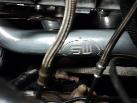 2004 Mercury Grand Marquis - Close-up of an engine part an SW logo and braided hoses.