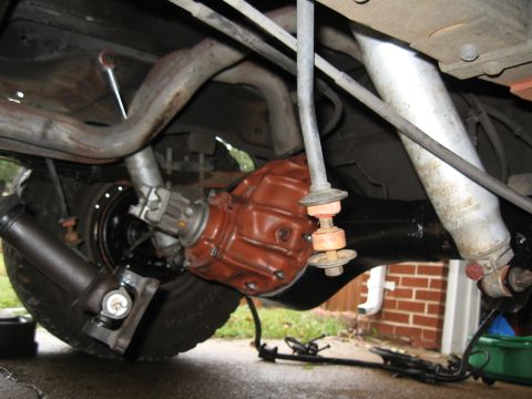 1994 Ford Bronco - Vehicle undercarriage showing a red-painted rear differential, driveshaft, exhaust pipes and U-joint.