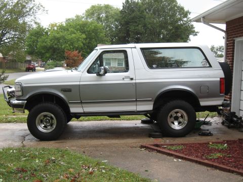 1994 Ford Bronco - This two-tone Ford Bronco is parked on a driveway, appearing to be undergoing some maintenance.